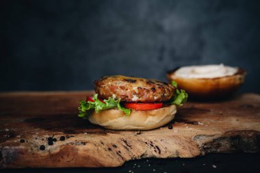 Burger with marinated onion and truffle paste on wooden board and dark background