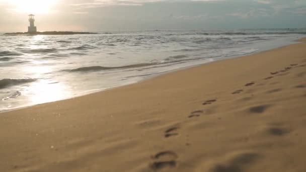 Arena paisaje de playa al atardecer. Olas en el mar. Faro — Vídeo de stock