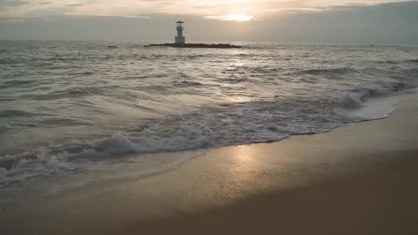 Arena paisaje de playa al atardecer. Olas en el mar. Faro — Vídeo de stock