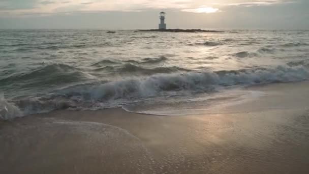 Piaszczysty krajobraz plaży o zachodzie słońca. Fale na morzu. Latarnia morska — Wideo stockowe