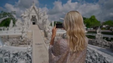 Chiang Rai, Tayland - 17 Temmuz 2020: Beyaz Tapınak olarak bilinen Wat Rong Khun 'un resmini yapan kadın turist. El kamerasıyla.