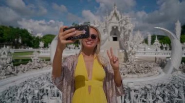 Chiang Rai, Tayland - 17 Temmuz 2020: Beyaz Tapınak olarak bilinen Wat Rong Khun 'da selfie çeken kadın turist. El kamerasıyla.