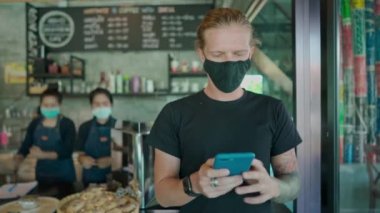Tayland 'da kafede siyah maskeli bir adam telefonuyla sohbet ediyor. El kamerasıyla.