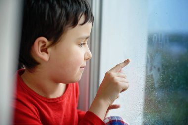 Pencereden bakan pijamalı hasta çocuk. Evde izolasyon. Evde kalıp koronavirüsü karantinaya alın. COVID-2019 Hastalık Konsepti