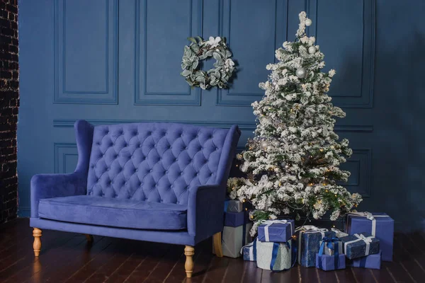 large blue living room with vintage sofa and Christmas tree. Beautiful New Year decorated home interior. blue boxes with gifts near the tree