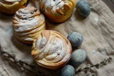 Geleneksel kek Paskalya pastası Kraffin. Koyu ahşap arka planda kuru üzümlü. Şekerli meyveli ev yapımı kek Cruffin. Doğal olarak mermer taşlı amber çiçeğiyle boyanmış yumurtalar..