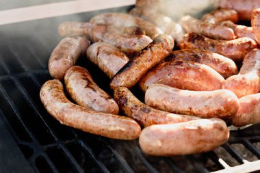 Izgara sosis ya da ızgara sosis, duman ve alevle. Barbekü ızgarasında lezzetli Alman sosisleri. Yaz pikniği, ızgaranın kapanışı, temiz hava konsepti. Bahçede barbekü.