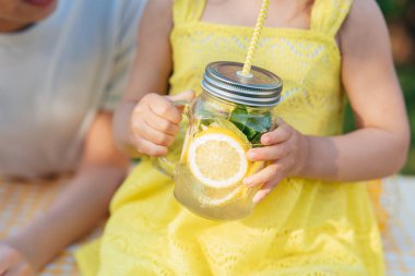 Çocuklar parkta doğal limonata içerler. Yaz ferahlatıcı doğal limonata. Detoks meyvesi aromalı su, içecek kutusunda taze meyveli kokteyl.