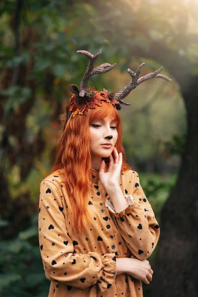 秋の森に鹿の角を持つ妖精の女性 フェイスペインティング 美しい謎の女性 大きな目の魔法の光景を持つ赤毛の女の子 — ストック写真