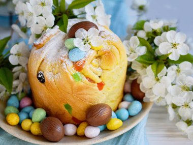 Geleneksel kek paskalya pastası Kraffin mavi arka planda kuru üzümlü. Kiraz çiçeği, çikolata yumurtası. Ev yapımı pastayı kapat. Şekerli meyveli Cruffin. Yiyecekler. Boşluğu kopyala.