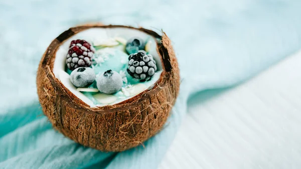 Healthy breakfast berry, banana smoothie bowl in coconut topped with Blueberries and chia seeds , superfood coconut delicious blueberry smoothie bowl. vegan raw food. Selective focus. copy space.