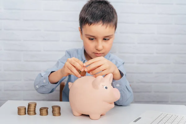 boy with pig piggy bank. childhood, money, investment and happy people concept. Child inserts coin into piggy bank. Selective focus.
