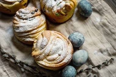 Geleneksel kek Paskalya pastası Kraffin. Koyu ahşap arka planda kuru üzümlü. Şekerli meyveli ev yapımı kek Cruffin. Doğal olarak mermer taşlı amber çiçeğiyle boyanmış yumurtalar..