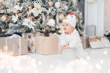 Mutlu tatiller, yeni yıl. Noel ağacının altında küçük bir çocuk. Kardan adam şapkalı bebek. Noel ağacının altında hediyeler ve hediyeler. Evde sıcak bir kış akşamı. Xmas zamanı.