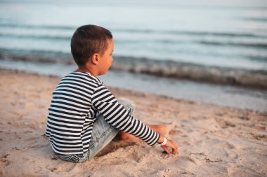 Denizde yaz tatili. Deniz kenarındaki çocuk. Çocuk plajda deniz kabuğu topluyor yaz tatilinde eğleniyor. Mutlu çocuk gün batımında oynuyor. Mutlu bir çocukluk. Seyahat ve macera konsepti
