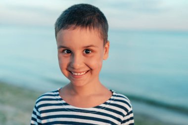 Denizde yaz tatili. Deniz kenarındaki çocuk. Çocuk plajda deniz kabuğu topluyor yaz tatilinde eğleniyor. Mutlu çocuk gün batımında oynuyor. Mutlu bir çocukluk. Seyahat ve macera konsepti