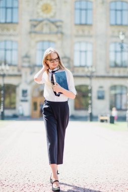 Kampüsteki üniversite öğrencisinin portresi. Genç öğrenci parkta ödev yaparken dizüstü bilgisayar kullanıyor. öğrenim ve eğitim kavramı