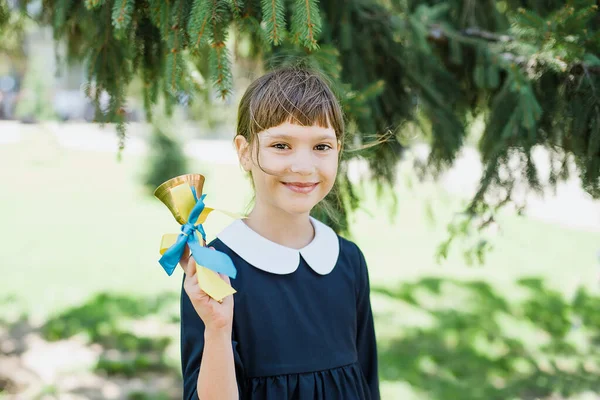 Portrait of beautiful young Schoolgirl on background school. Farewell Bell. day of knowledge. beginning of school year. Child with bell