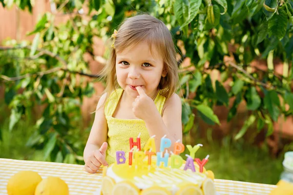 Birthday cake with happy birthday candles. Lemonade birthday party at summer park. food, celebration and festive concept. Little child drinks natural lemonade at stand in park