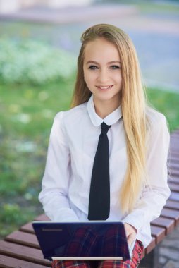 Kampüsteki üniversite öğrencisinin portresi. Genç öğrenci parkta ödev yaparken dizüstü bilgisayar kullanıyor. öğrenim ve eğitim kavramı