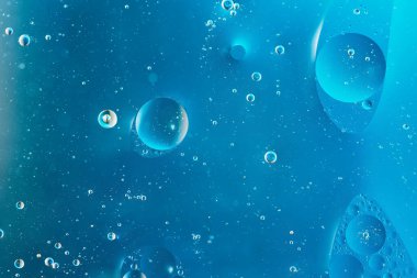 Koyu mavi arka planda köpüklü yağ. Soyut alan arkaplanı. Yumuşak seçici odaklanma. Su yüzeyine makro yağ damlaları. kopyalama alanı. Sudaki hava kabarcıkları