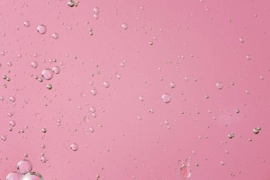 Açık pembe mercan tek renkli arka planda baloncuklu yağ. Soyut alan arkaplanı. Yumuşak seçici odaklanma. Şeffaf jel yüzeyine makro yağ damlaları. kopyalama alanı. Sudaki hava kabarcıkları,