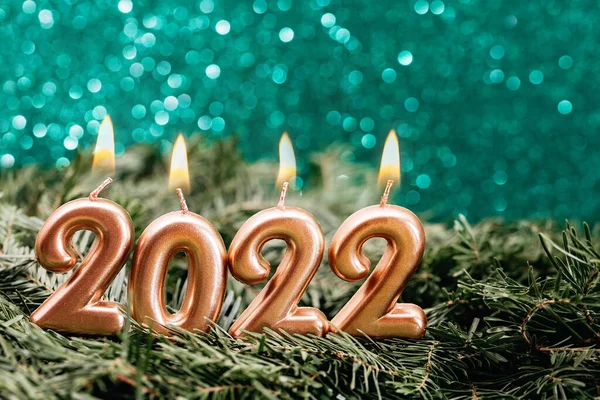 Holiday background Happy New Year 2022. Numbers of year 2022 made by gold burning candles on bokeh festive sparkling background. celebrating New Year holiday, close-up. Space for text