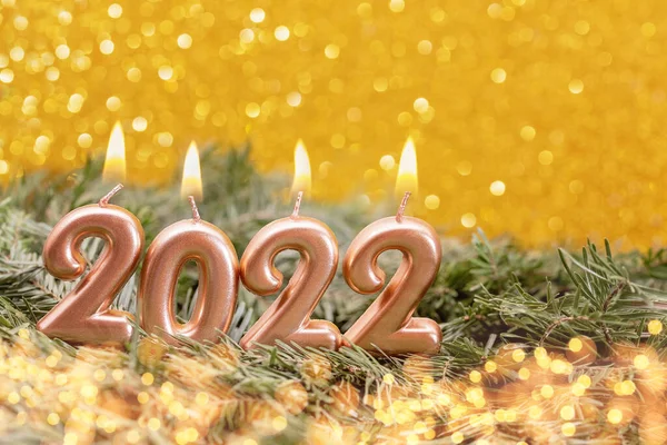 Holiday background Happy New Year 2022. Numbers of year 2022 made by gold burning candles on bokeh festive sparkling background. celebrating New Year holiday, close-up. Space for text