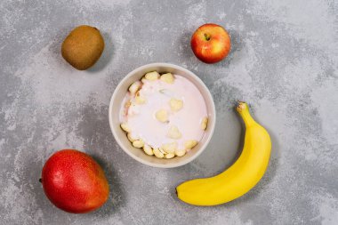 Sağlıklı gıda tanecikleri kasede. Taze granola, kivili müsli, arka planda gri kasede muz ve fındık. Evde pişirme hazırlıkları, hepsi kasenin içinde. Düz yatıyordu, yukarıdan, yukarıdan..
