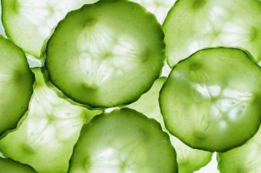 Salatalıklı arka plan. Taze salatalık dilimlerinin üst görünüm doku arkaplanını kapatın. Yüzüklere kesilmiş taze salatalık.