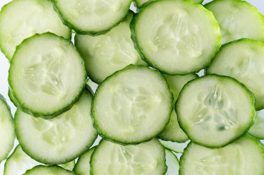 Salatalıklı arka plan. Taze salatalık dilimlerinin üst görünüm doku arkaplanını kapatın. Yüzüklere kesilmiş taze salatalık.