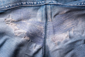 Detailní roztrhané staré modré džíny pozadí. textura roztrhaných poškozených džínů. díra a šmouhy na džínách mezi nohama. opravy šicím strojem a šitím