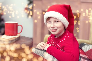 Mutlu çocuk Noel arifesinde heyecanlı. Umut Noel Baba 'yı bekliyor. Umutlu çocuk. Yeni yıl arifesi. Hayaller gerçek olur. Kırmızı bardak sıcak kakaolu çocuk mu yoksa şekerli çikolata mı?.