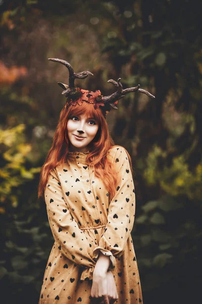 秋の森に鹿の角を持つ妖精の女性 フェイスペインティング 美しい謎の女性 大きな目の魔法の光景を持つ赤毛の女の子 — ストック写真