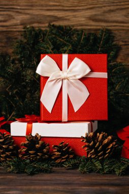 Noel tatili arka planında, dekorasyonlar ve hediye kutuları ile ahşap tahtada ışıl ışıl parlıyor. Yeni yılı kutluyoruz, yakın plan. Kırmızı kurdele ve ladin dalı. Kış Xmas tatil teması.