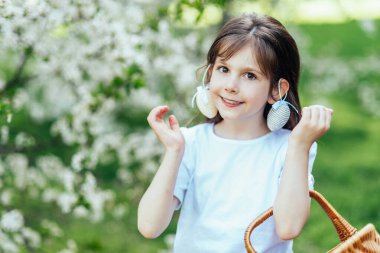 Paskalya yumurtası avında elinde paskalya sepeti tutan mutlu çocuk portresi. Neşeli açık hava aile anı Paskalya, çocukluk ve mevsimlik gelenekleri kutluyor..