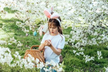 Paskalya yumurtası avı konsepti. Paskalya kutlaması. Çocuklar renkli yumurtaları sepette topluyorlar. İyi tatiller..