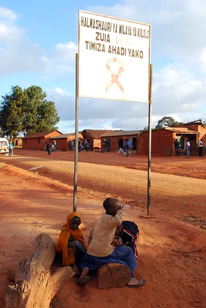 Algumas crianças sob o signo de zona de AIDS na entrada da Vila de Pomerini-Tanzânia-África — Fotografia de Stock
