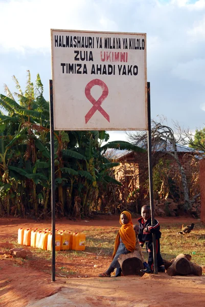 Některé děti ve znamení aids zóny u vchodu do vesnice pomerini Tanzanie Afrika — Stock fotografie