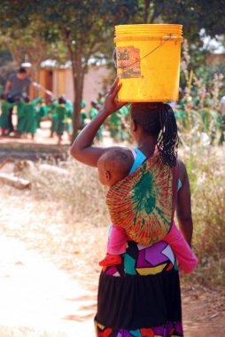 Bir anne çocuğunu, wa bir kova ile ortak bir çeşme ile