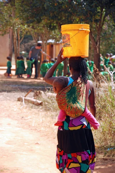 Une mère avec son enfant à une fontaine publique avec un seau de wa — Photo