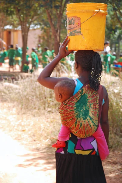 Bir anne çocuğunu, wa bir kova ile ortak bir çeşme ile