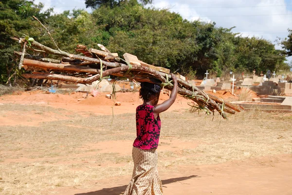 Una mujer africana cargando la leña para el fuego — Foto de Stock