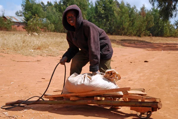 Uma criança africana para trabalhar com seu carrinho de mão — Fotografia de Stock