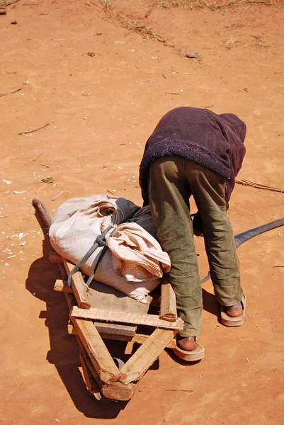 Un bambino africano al lavoro con la carriola — Foto Stock