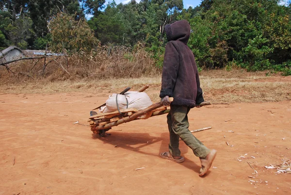 Un bambino africano al lavoro con la carriola — Foto Stock