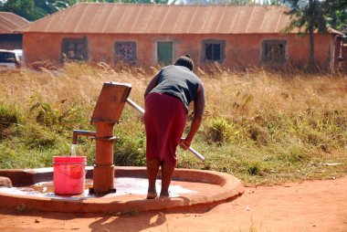 Bir kadın ve pompa su genel bir çeşme-Pomerini-Tanzanya-