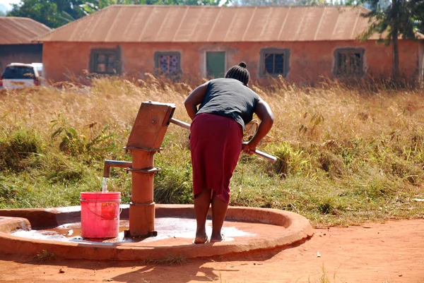 Una mujer y bombear agua de una fuente pública-Pomerini-Tanzania - — Foto de Stock