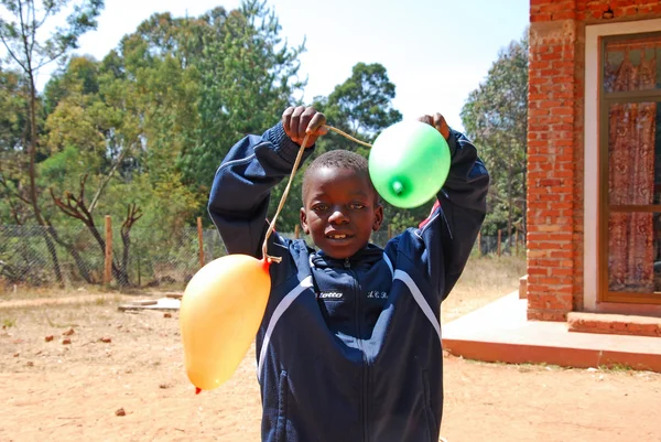 Un bambino africano gioca con palloncini colorati-Pomerini-Tanzania-A — Foto Stock