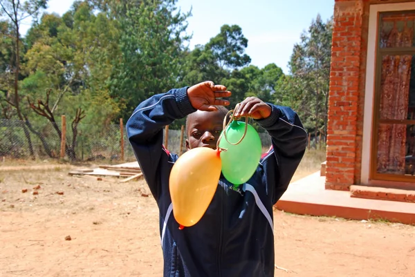 Un bambino africano gioca con palloncini colorati-Pomerini-Tanzania-A — Foto Stock